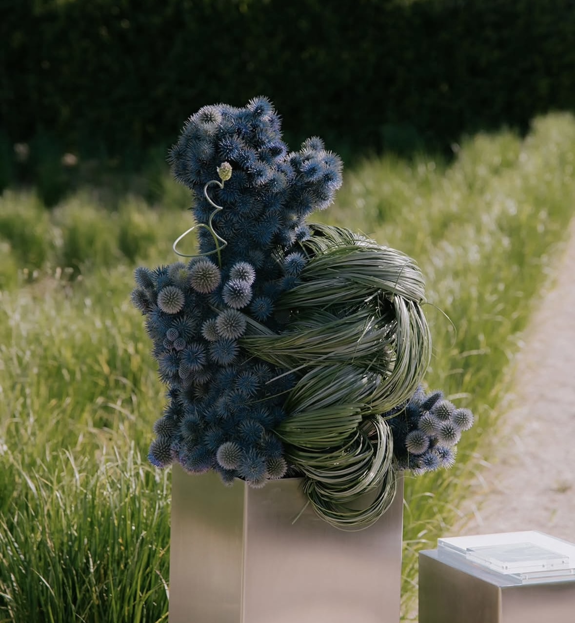 Sculptural thistle and grass installation in a garden setting